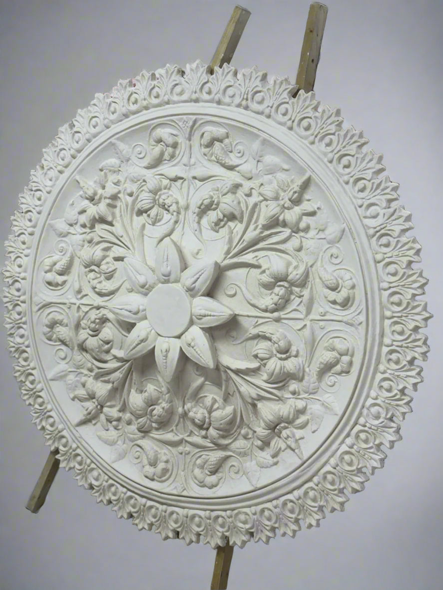 Decorative stone wall art piece with intricate patterns on a construction site background.