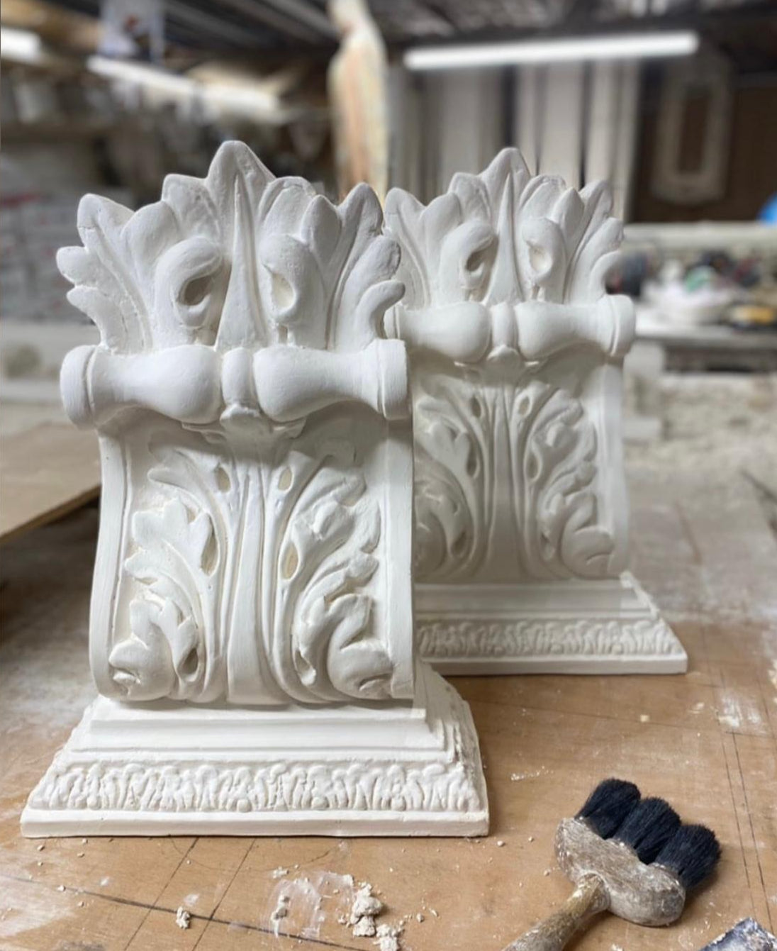 Decorative white architectural element on a wooden surface with tools in the background